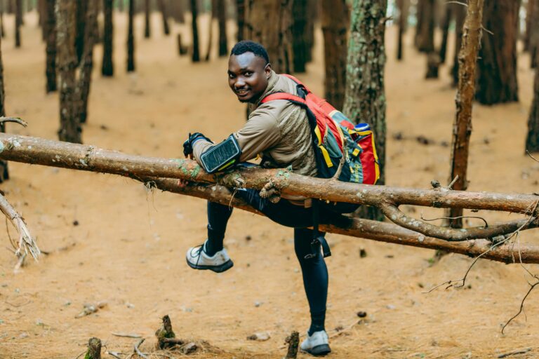 Energetic man hiking through a forest, cheerful expression, autumn setting.