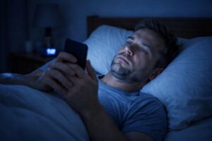 person using smartphone at night with blue light affecting sleep quality