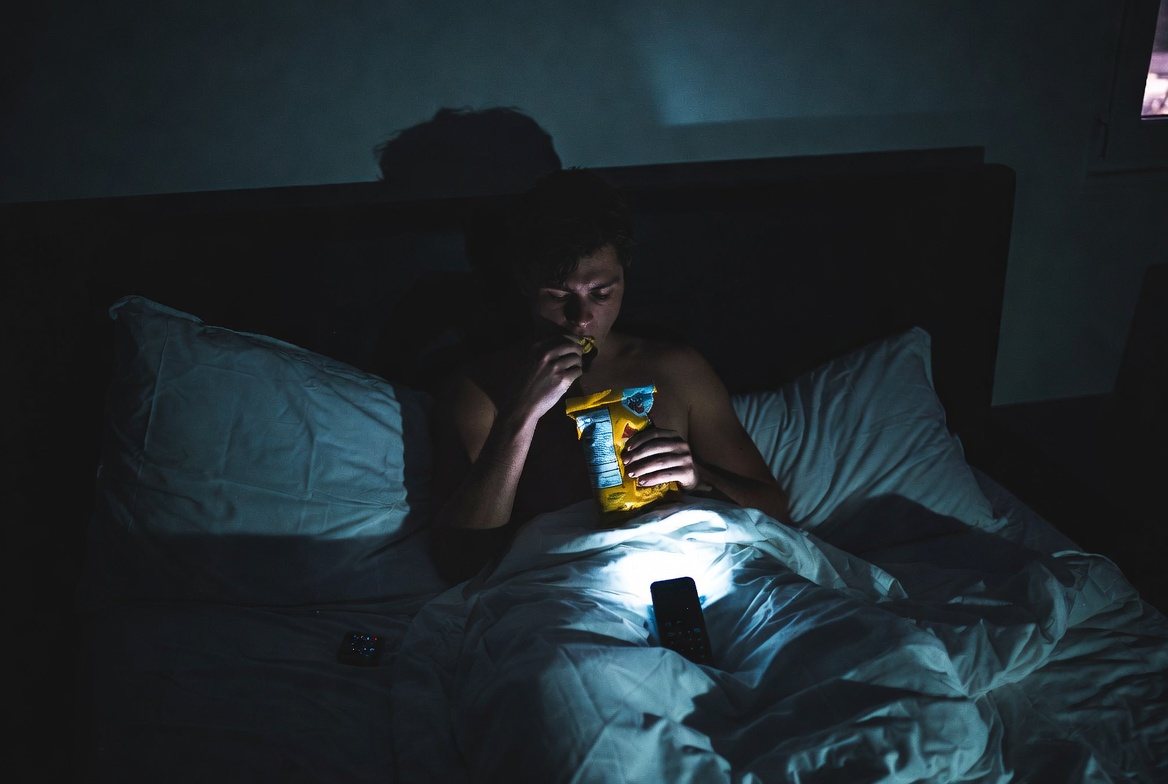 person eating food in bed at night affecting sleep quality