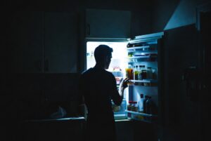 person opening fridge at night looking for food late night