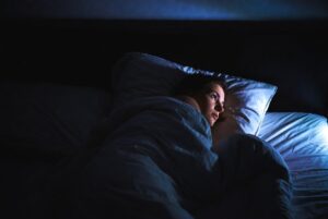 person lying awake in bed overthinking and unable to fall asleep
